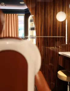 Détail d’un miroir à contour arrondi au Negresco, entre boiseries et fauteuil de salon.