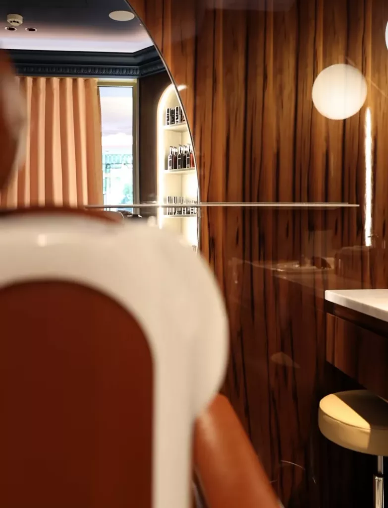 Détail d’un miroir à contour arrondi au Negresco, entre boiseries et fauteuil de salon.